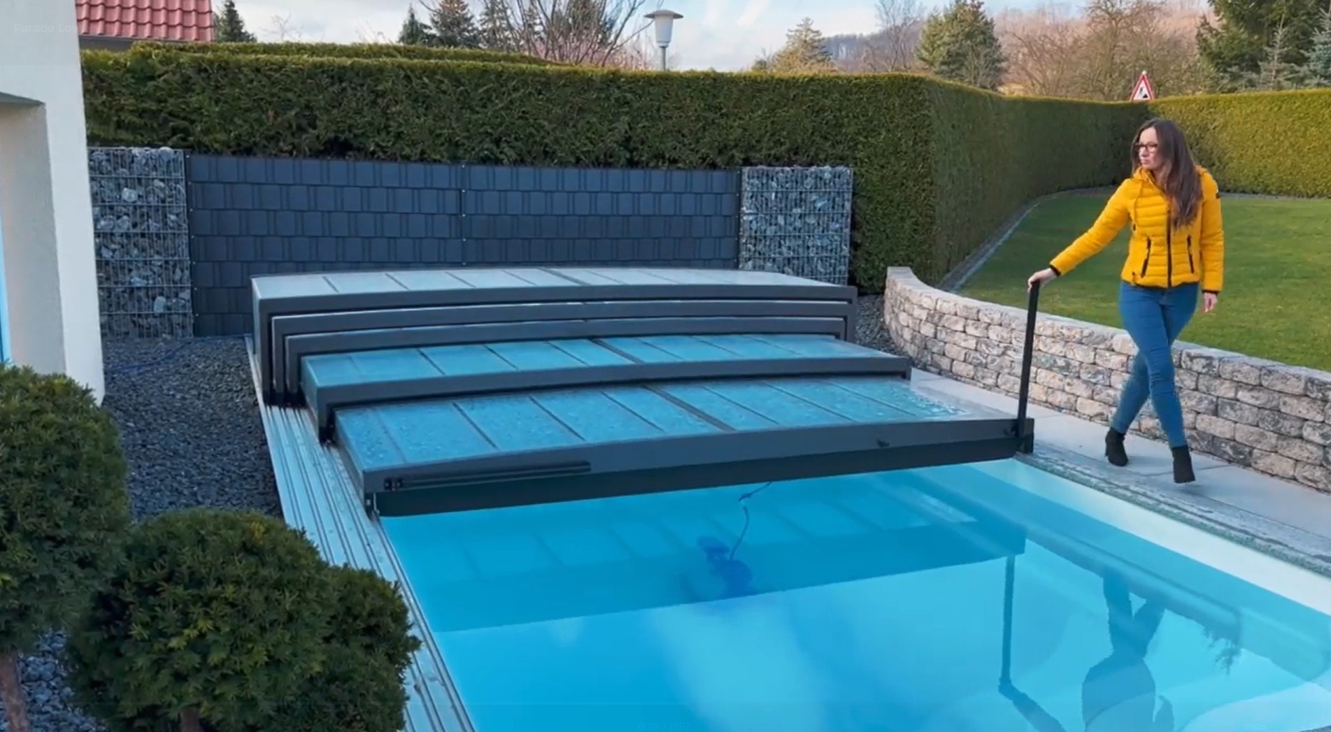 Uživatel posouvá segment zastřešení Parade Low pomocí praktického sklopného madla pro pohodlnou manipulaci